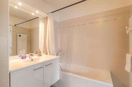 La salle de bains blanche est pourvue d'un lavabo et d'une baignoire. dans l'établissement Cosy avec parking proche Brotteaux, à Lyon