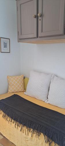 un lit avec deux oreillers et une armoire au-dessus dans l'établissement Coeur du village Barcarès accès plage direct studio vue mer exceptionnelle, au Barcarès