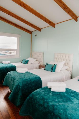 a room with three beds with green sheets at Cabañas Arte Brisa Patagonia in Puerto Natales