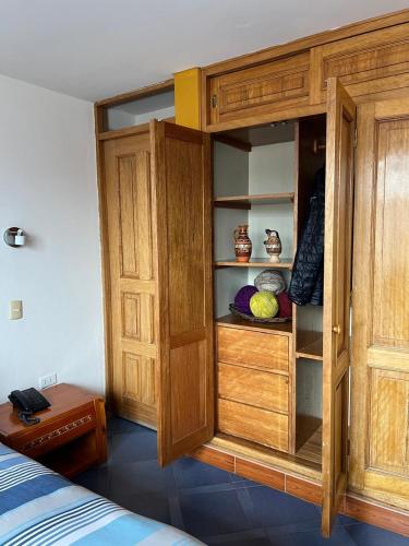 a wooden cabinet in a room with a bed at Yanapanakusun Cusco in Cusco