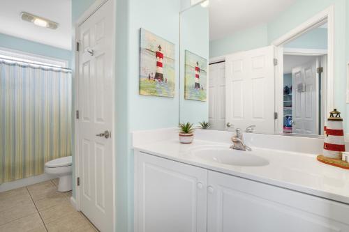 a white bathroom with a sink and a toilet at Seas the Day - Water views, Shared pool! in Chincoteague
