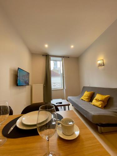 - un salon avec un lit et une table avec des verres à vin dans l'établissement Appart'Village Le vieux Vichy centre T1,T2,T3 - Parking - Thermes, à Vichy