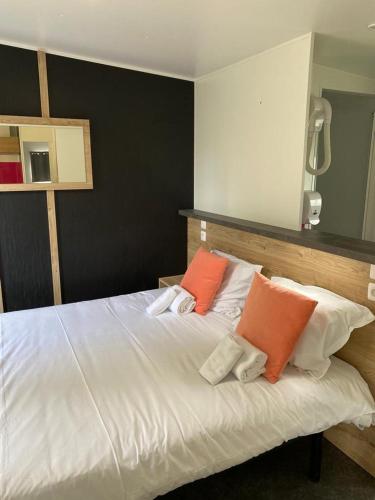 - une chambre avec un lit blanc et deux oreillers orange dans l'établissement Pôle Européen du Cheval - Les Cottages du Haras, à Yvré-lʼÉvêque