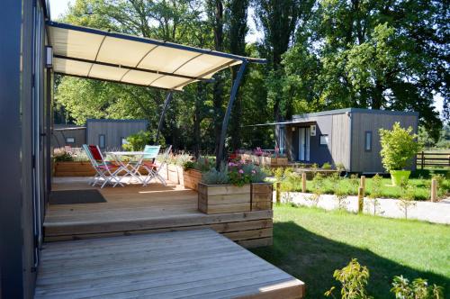 une terrasse avec auvent, une table et des chaises dans l'établissement Pôle Européen du Cheval - Les Cottages du Haras, à Yvré-lʼÉvêque