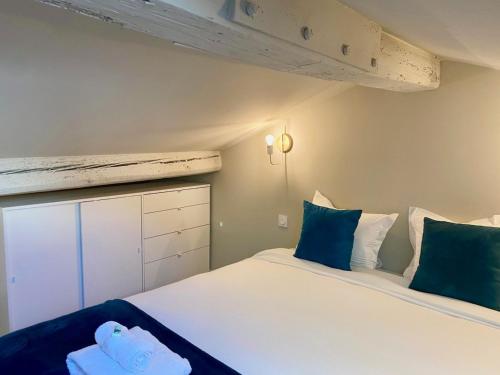 une chambre avec un grand lit blanc avec des oreillers bleus dans l'établissement 'La Perrière' Joli T2 en duplex Clim, Wifi, à Sète