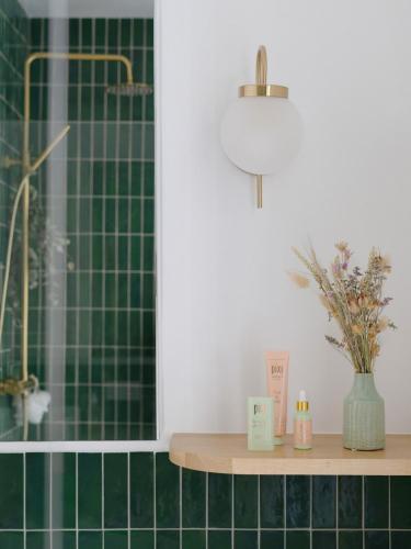 La salle de bains est pourvue de murs carrelés verts et d'une étagère avec des bougies. dans l'établissement Minimalist Haussmannian Paris 11, à Paris