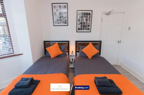two beds in a room with orange pillows at Award-Winning Four Bedrooms House, Parking, WiFi By Derby Short Term Rental Short Lets & Serviced Accommodation Derby in Derby