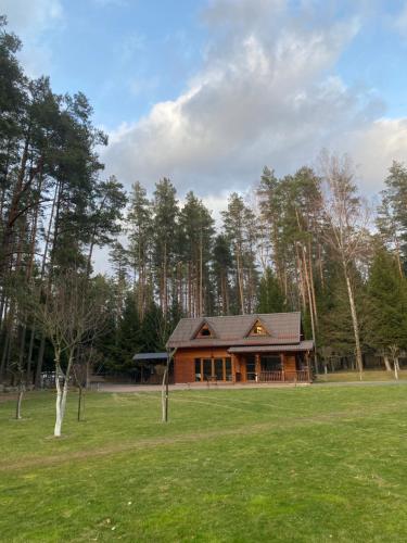 a large wooden house in a field with trees at Dzūkų sodžius in Snaigupė