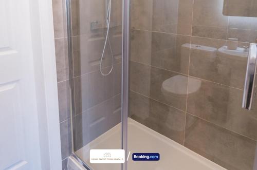 a shower with a glass door and a toilet at Award-Winning Four Bedrooms House, Parking, WiFi By Derby Short Term Rental Short Lets & Serviced Accommodation Derby in Derby
