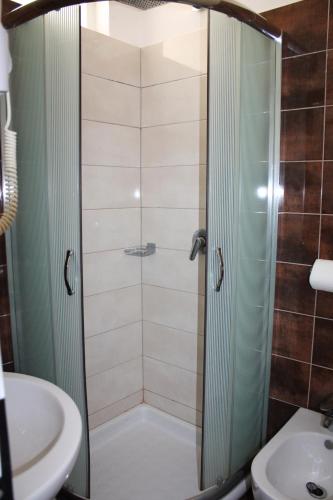 a shower with a glass door next to a sink at Hotel Nimfa in Vlorë