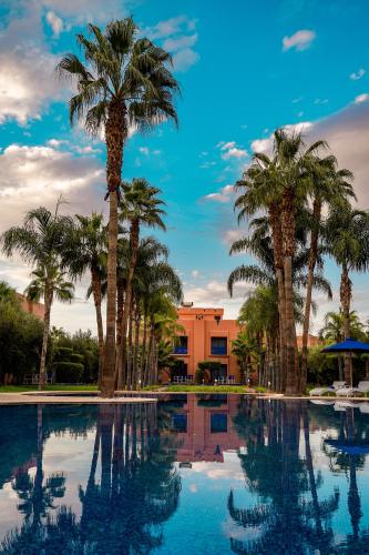 Una piscina con palmeras y un edificio. en Palais Volteras, en Marrakech