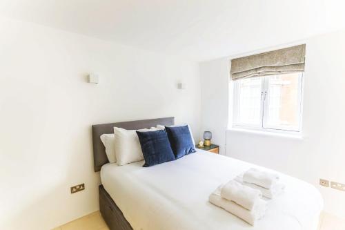 a bedroom with a white bed with blue pillows at Accomodo London Soho - Elegant Apartments near Carnaby Street and Oxford Street in London