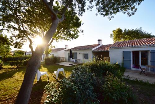 a house with a tree in the yard at Le Parc des Mimosas in Noirmoutier-en-l'lle