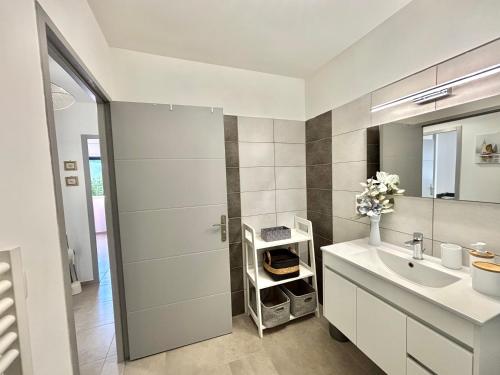 une salle de bain blanche avec un lavabo et un miroir dans l'établissement Villa Le Rotolo PORTICCIO, à Porticcio