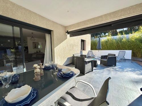 un patio avec une table et des chaises sur un patio dans l'établissement Villa Le Rotolo PORTICCIO, à Porticcio