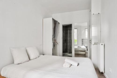 - une chambre blanche avec un lit et un miroir dans l'établissement Superb 1BR flat 2min walk from the metro station, à Paris