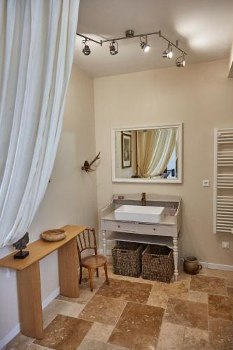 La salle de bains est pourvue d'un lavabo, d'un bureau et d'un miroir. dans l'établissement Maison de Vacances avec piscine en Normandie, à Rugles