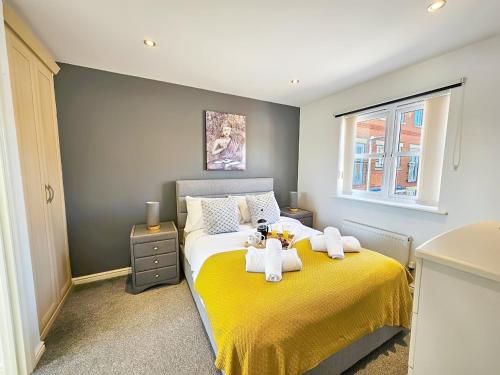 a bedroom with a yellow bed with towels on it at Boughton 3 Bed Semi by Fortuna Property in Gloucester