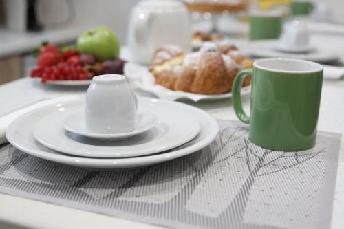 a table with plates and a cup and a coffee mug at Domus Aurea in Reggio Calabria