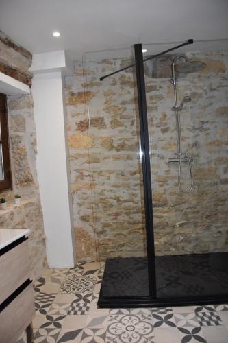 a shower in a bathroom with a stone wall at Sous les étoiles du Causse in Espédaillac