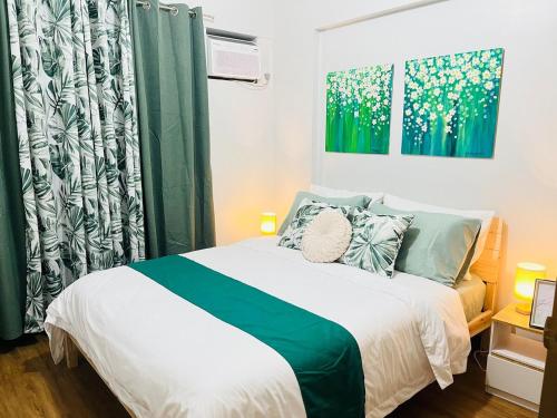 ein Schlafzimmer mit einem Bett mit grün-weißer Bettwäsche in der Unterkunft Acacia Estates' The Getaway Taguig, Evergreen in Manila