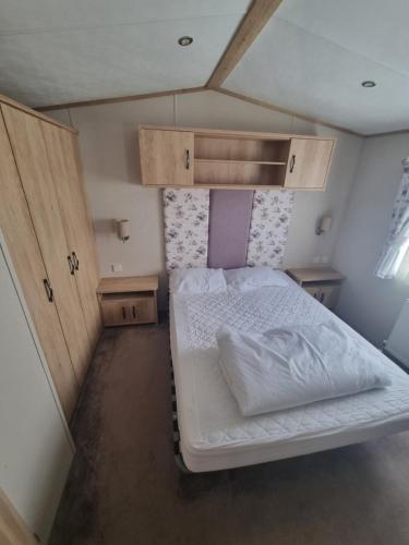 ein kleines Schlafzimmer mit einem weißen Bett und Holzschränken in der Unterkunft A beautiful 4 birth - 714 Unity Beach Holiday Resort Unity 2 pets stay free in Brean