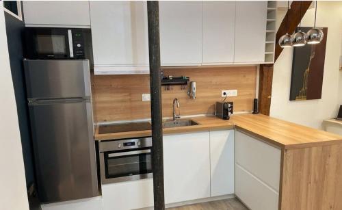 une cuisine avec des armoires blanches et un réfrigérateur en acier inoxydable dans l'établissement Apartment on Rue Morvan, à Paris