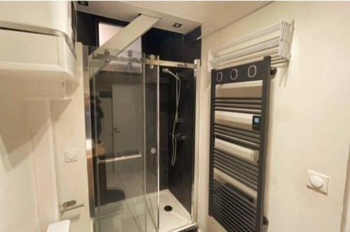 une douche dans une salle de bain avec une porte vitrée dans l'établissement Apartment on Rue Morvan, à Paris