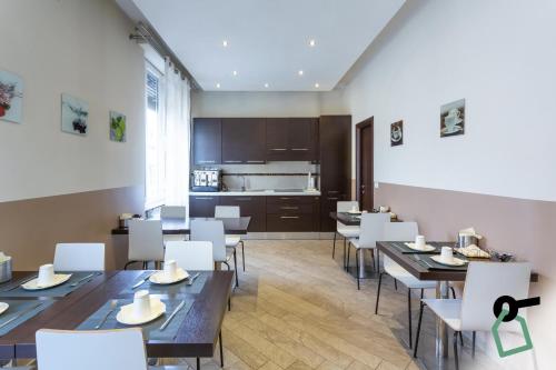 een restaurant met tafels en witte stoelen en een keuken bij HOTIDAY Room Collection - Roma Barberini in Rome