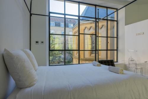 a white bed in a room with a large window at Loft de la Chapelle Sainte Blandine in Metz
