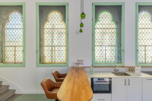 - une cuisine avec une table en bois et deux vitraux dans l'établissement Loft de la Chapelle Sainte Blandine, à Metz