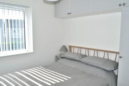 ein Bett in einem weißen Schlafzimmer mit Fenster in der Unterkunft 2 Rosemullion in Perranporth