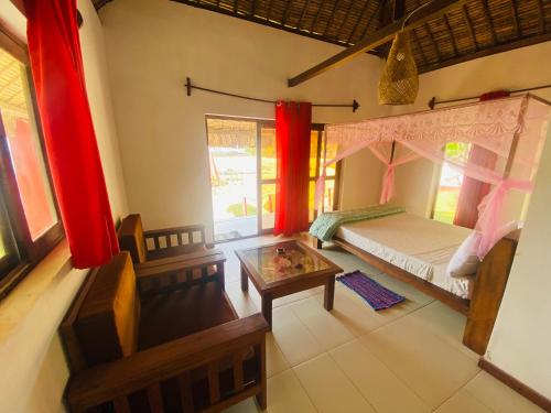 a bedroom with a bed and a coffee table at Nosy-Borah Holidays in Analabe