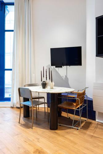 d'une salle à manger avec une table, des chaises et une télévision. dans l'établissement Magnificent apartment - 1BR-6P - Sentier, à Paris