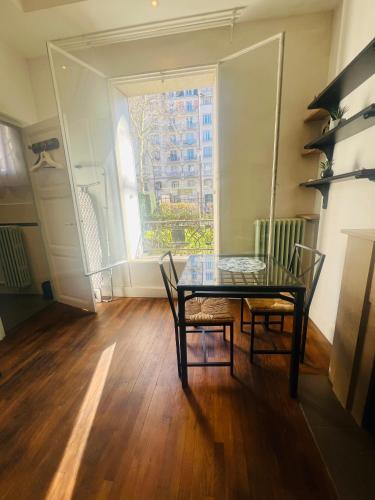 une salle à manger avec une table et des chaises et une fenêtre dans l'établissement Studio Auteuil Suchet Paris, à Paris