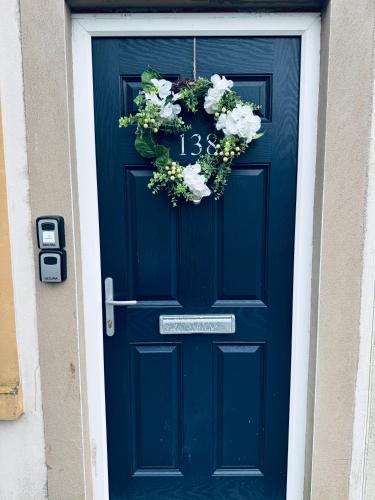 a blue door with a wreath of flowers on it at Queens Townhouse - 4 Bedrooms - Sleeps 9 in Whitehaven