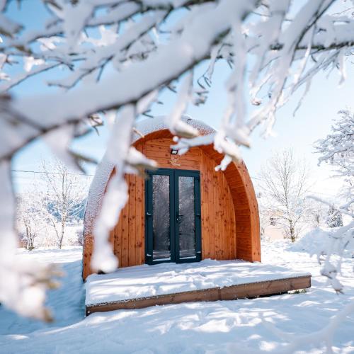 a wooden building in the snow with snow covered branches at Gite L'insolite dans le Jura in Étival