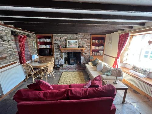 a living room with a red couch and a fireplace at Quiet cottage on the rural edge of Brixham in Brixham