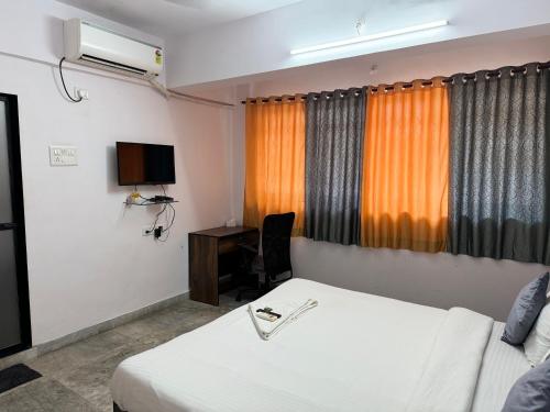 a room with a bed and a desk and a television at Sadanand Home in Navi Mumbai