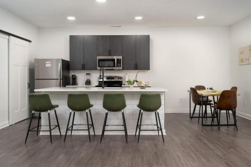 a kitchen with green bar stools and a counter at Golden Sun Spacious 1BR Pond View King Bed WFH Gym in Whitestown