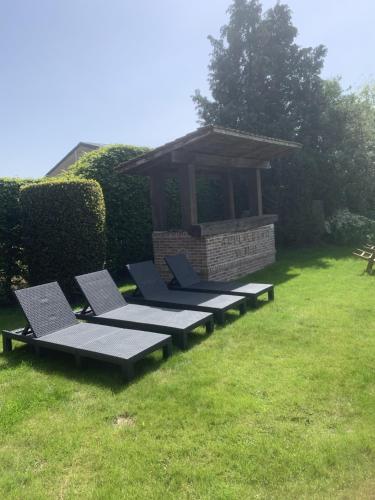 a group of lounge chairs in a yard with a gazebo at A l'Etang du Trieu in Pecq