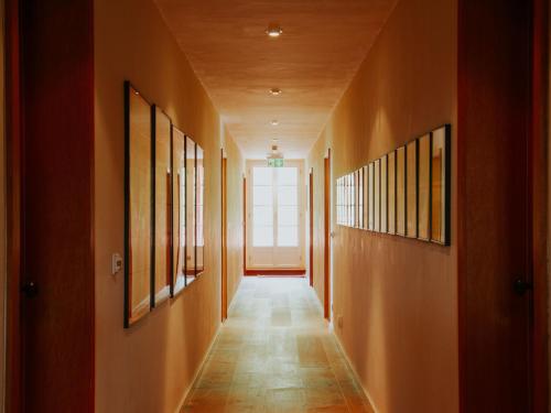 a hallway with orange walls and a long hallway with paintings at Landhaus Alte Schmiede in Niemegk
