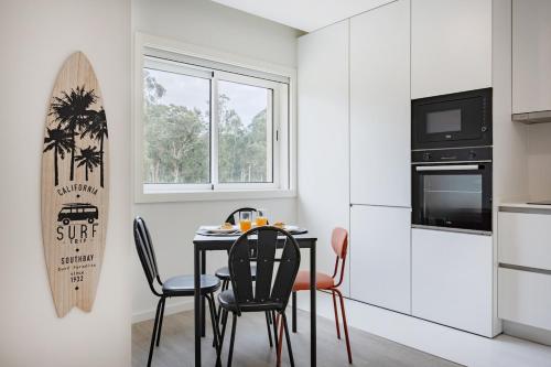 オバールにあるFuradouro Pine & Sea with Swimming Pool Studio 1のキッチン(テーブル、椅子、壁にサーフボード付)