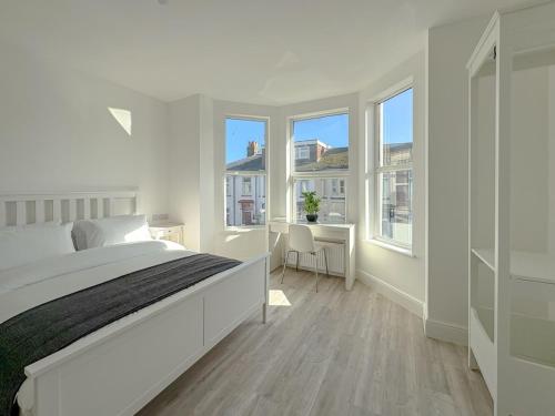 a white bedroom with a large bed and windows at Nelson Road - 3 Bed Terrace in Yarmouth in Great Yarmouth