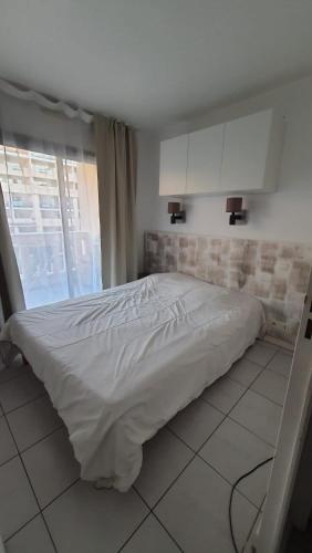 un lit blanc dans une chambre avec une fenêtre dans l'établissement Appartement T2 bord de mer piscine 2025, à Cannes