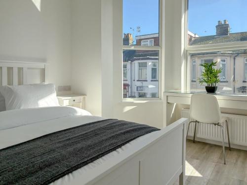 a white bedroom with a bed and a desk and a window at Nelson Road - 3 Bed Terrace in Yarmouth in Great Yarmouth
