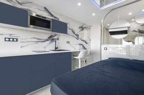 - une chambre avec un lit bleu et un lavabo dans l'établissement Naturiste Cap d'Agde Héliopolis F 49, au Cap d'Agde