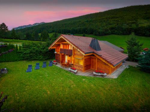 a log cabin in a field with a sunset at Chalet J'Elage - OVO Network in Saint-Jean-de-Sixt