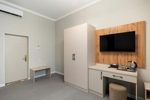 a room with a desk and a tv on a wall at Cozy Hotel in Bishkek