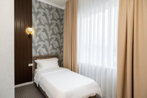 a bedroom with a white bed and a window at Cozy Hotel in Bishkek